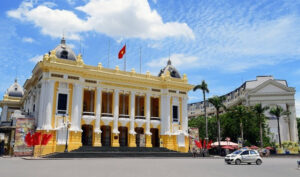 a yellow building with white pillars and a flag on the front