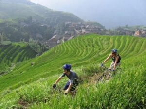 two people riding bikes on a hill