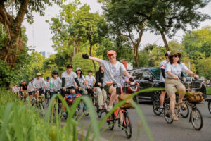 The leisurely atmosphere of cycling in Hanoi, particularly focusing on the flower-carrying bicycles along Thuy Khue – Mai Xuan Thuong streets. These bicycles contribute to a unique characteristic of the city with their vibrant colors and serene presence, alleviating the fatigue of street vendors and fostering a sense of harmony and freshness in the neighborhood.